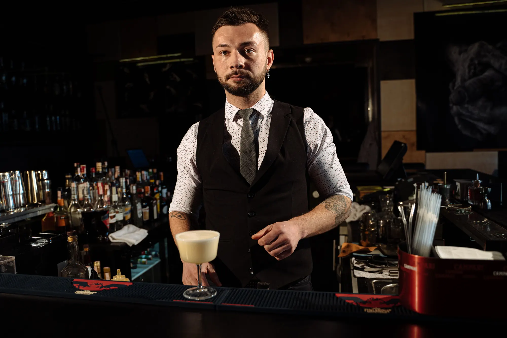 A bartender finishing cocktails at a dimly lit bar
