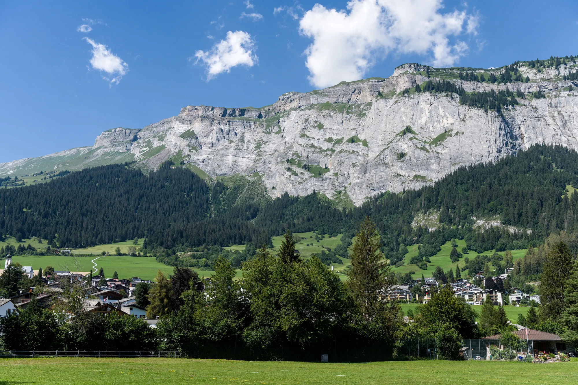 An alpine village below the mountains in clear summer light