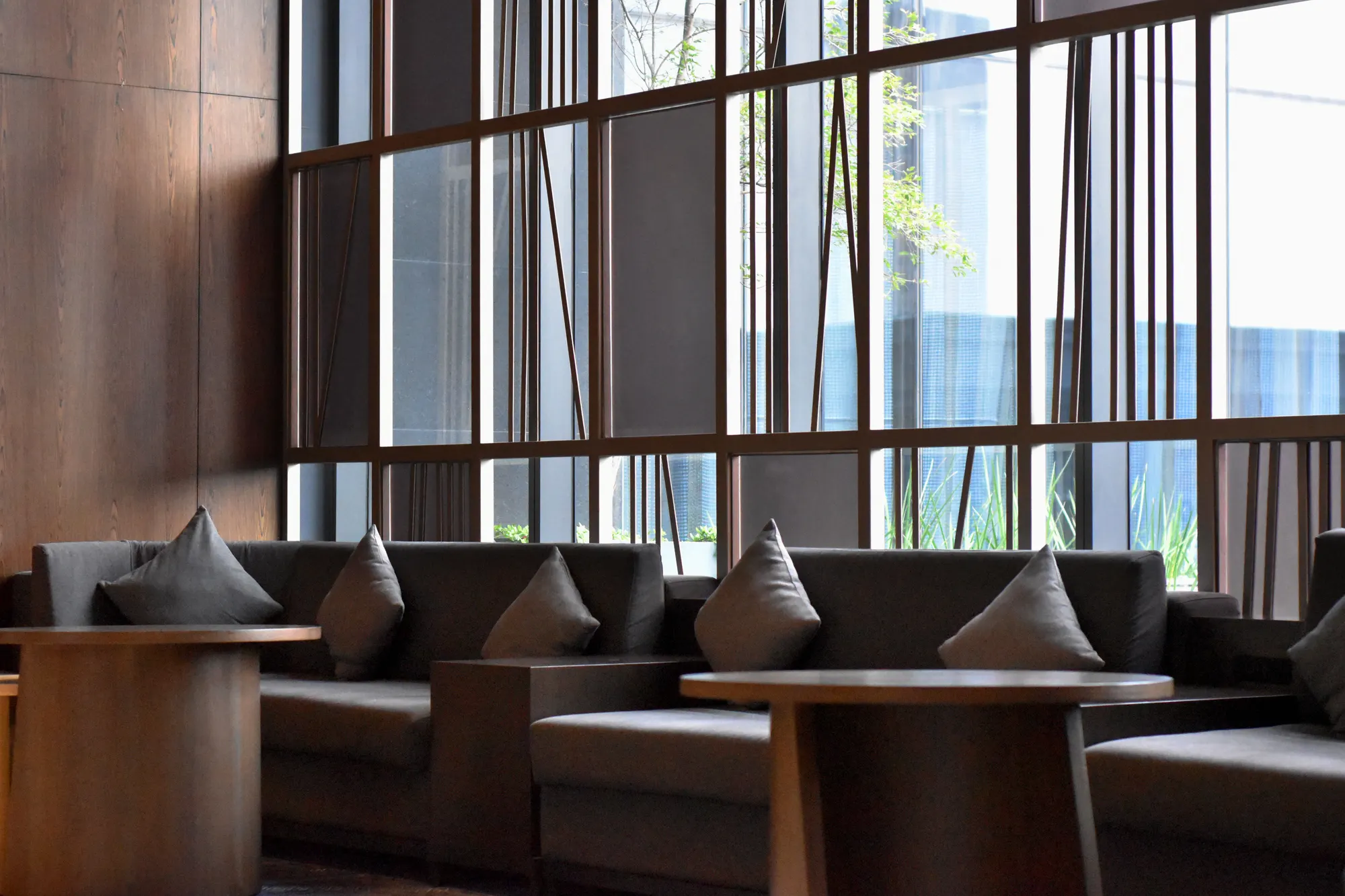 The lounge of a modern hotel lobby, tall windows onto the street