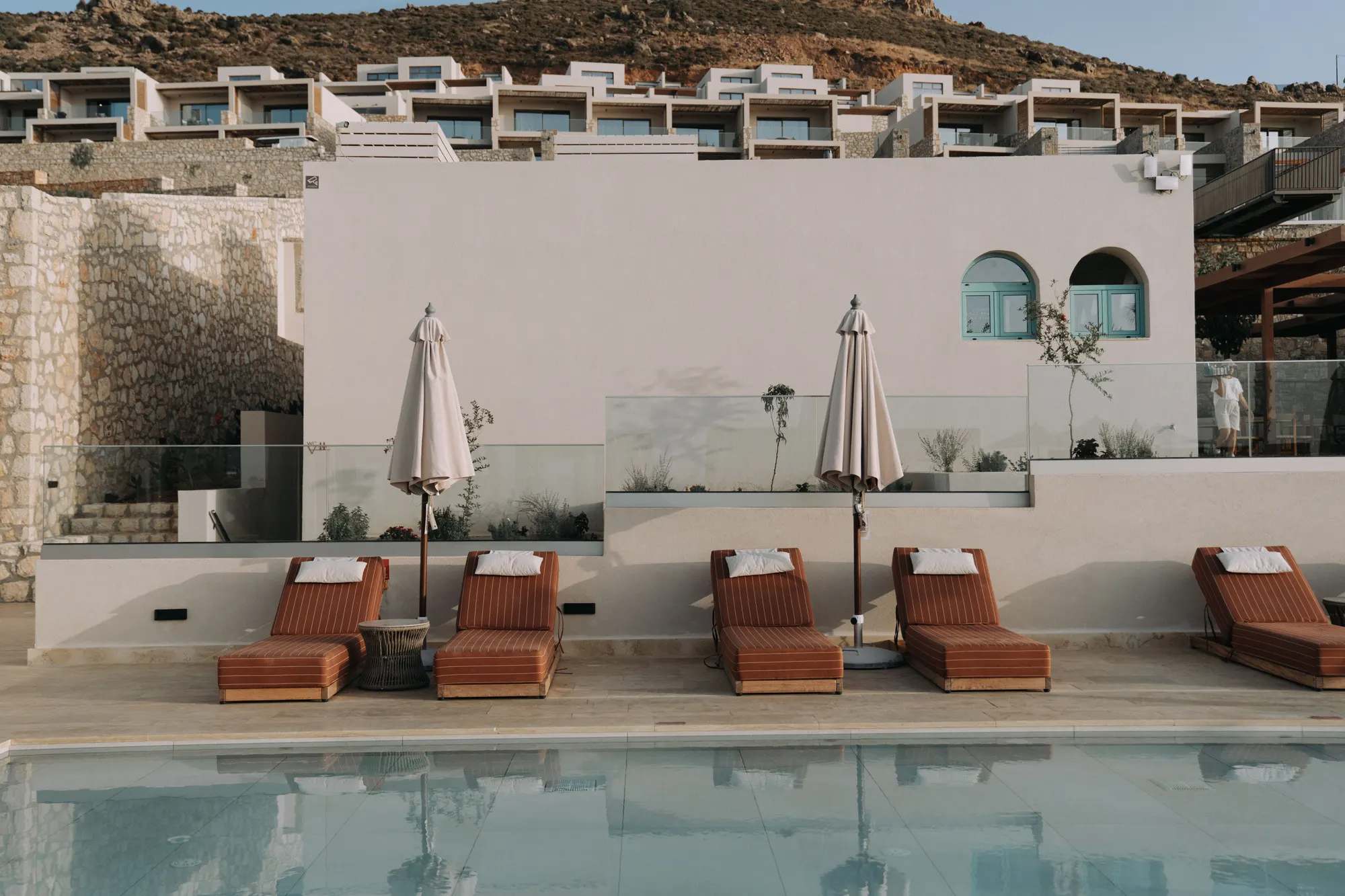 A hotel pool terrace with loungers set out along the water