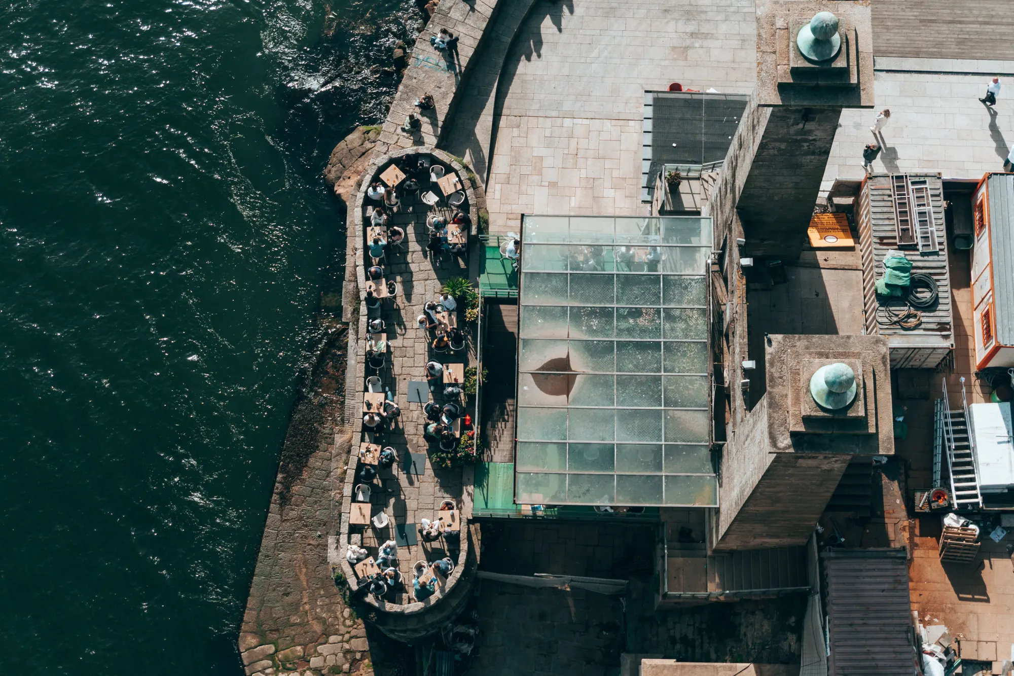 An outdoor restaurant terrace set for dinner beside the water