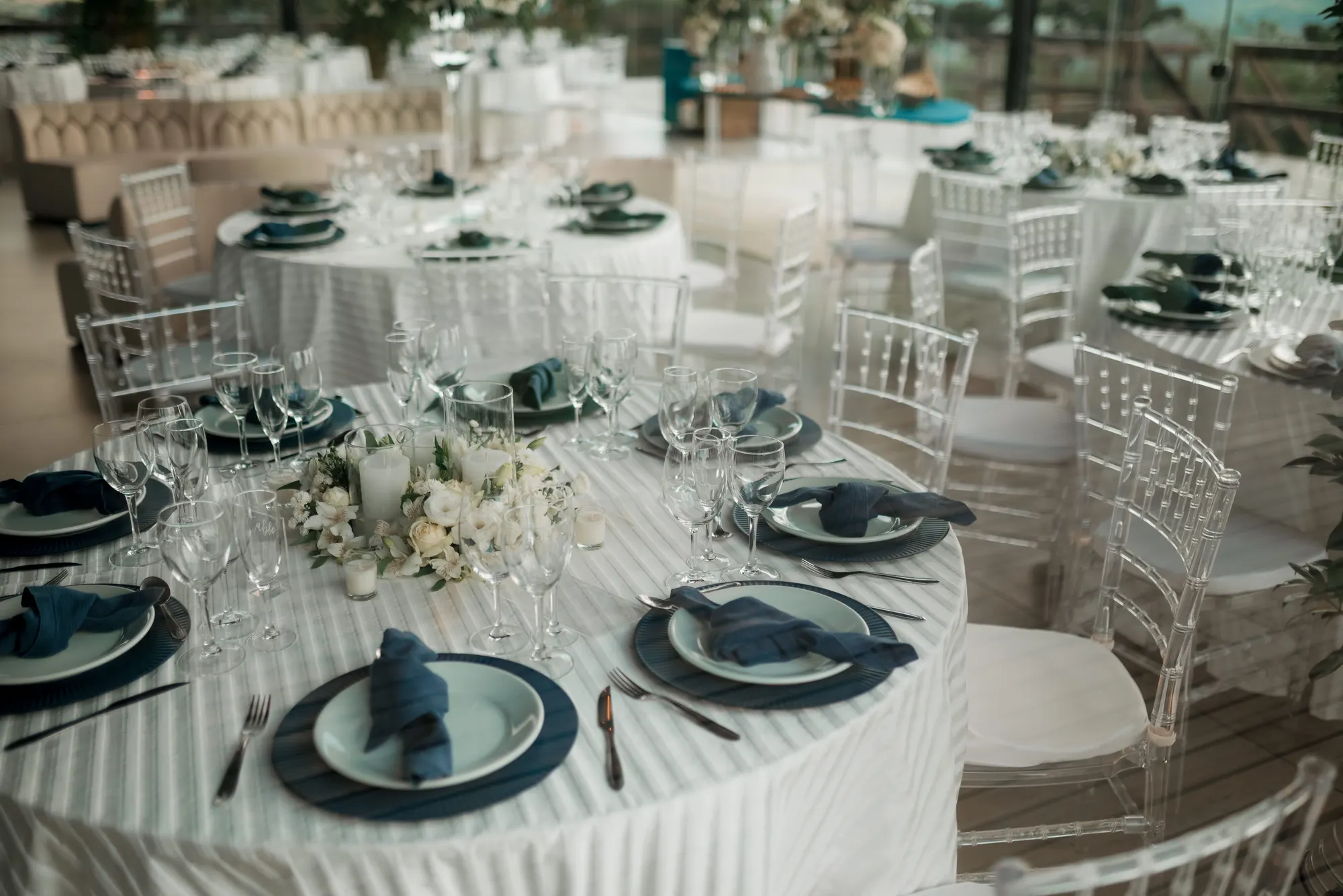 A wedding reception room set with long tables and floral centrepieces